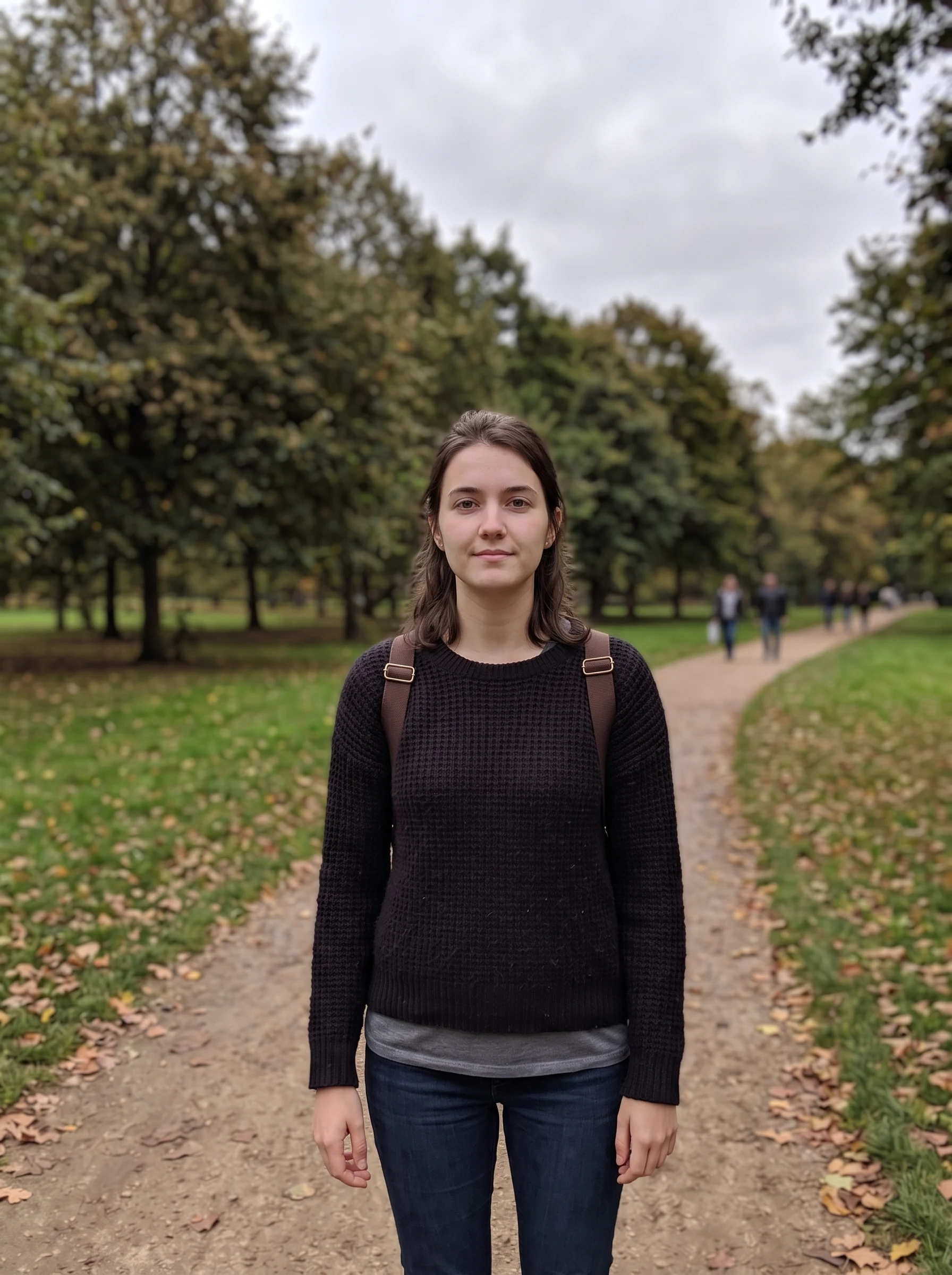 The same woman on the same path now facing the camera squarely, park and light unchanged