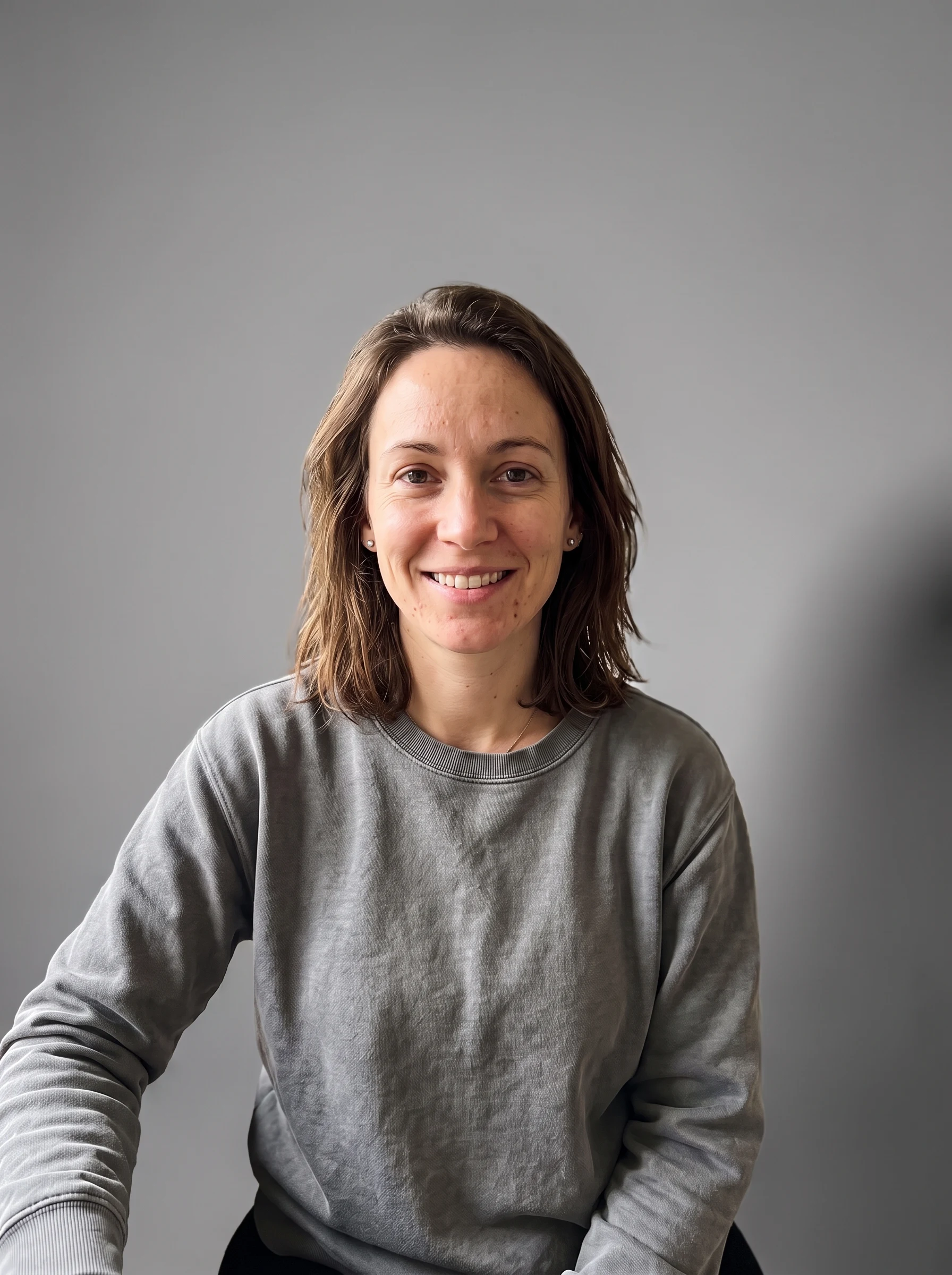 The same woman on a clean neutral-grey studio backdrop, relit with a soft key light and side shadow