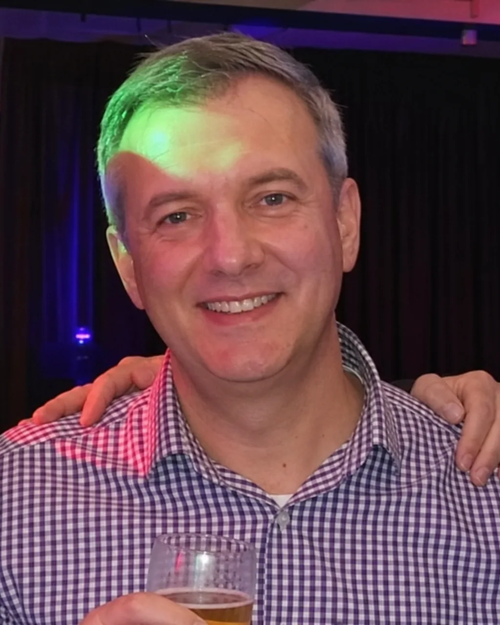 Man cropped from a group photo at a party with strangers still visible at the edges