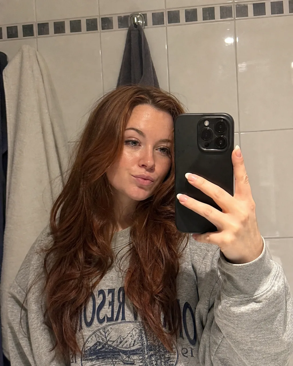 Bathroom mirror selfie with the phone visible in frame before AI dating photo generation