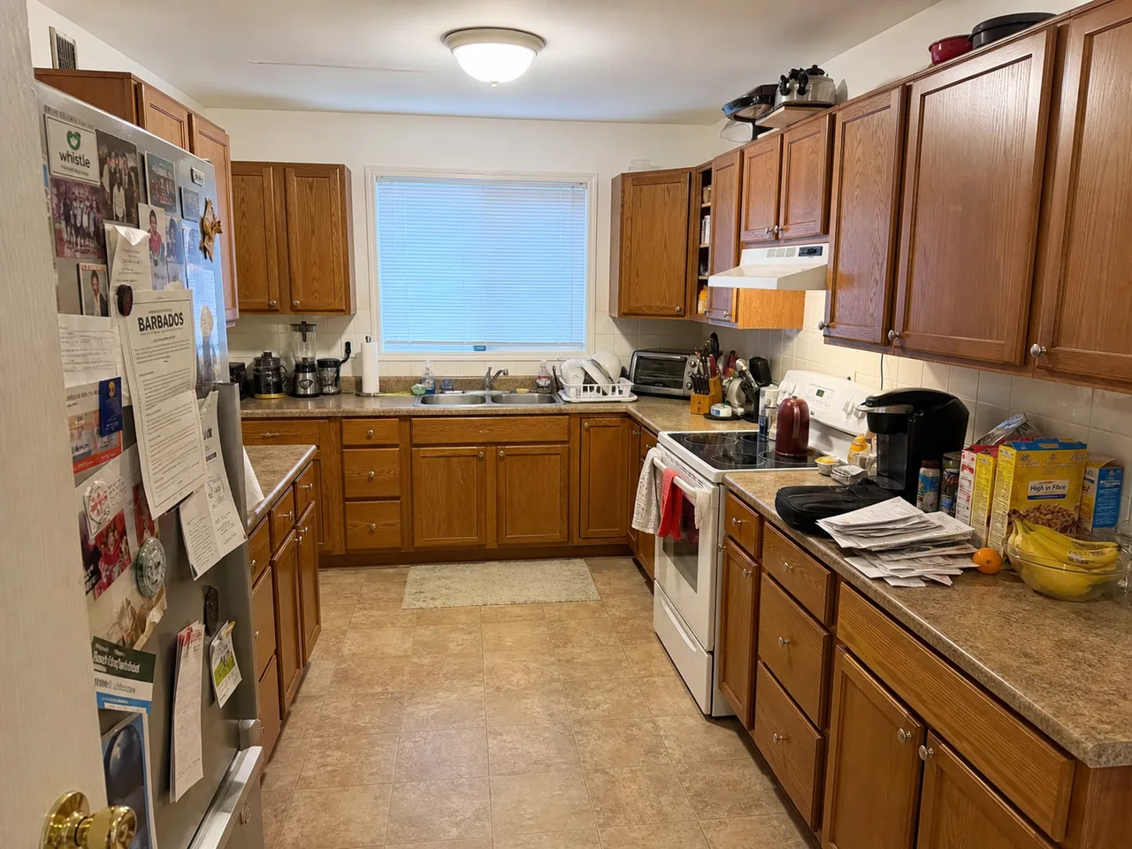 Occupied kitchen with cluttered countertops and a covered fridge door before AI decluttering