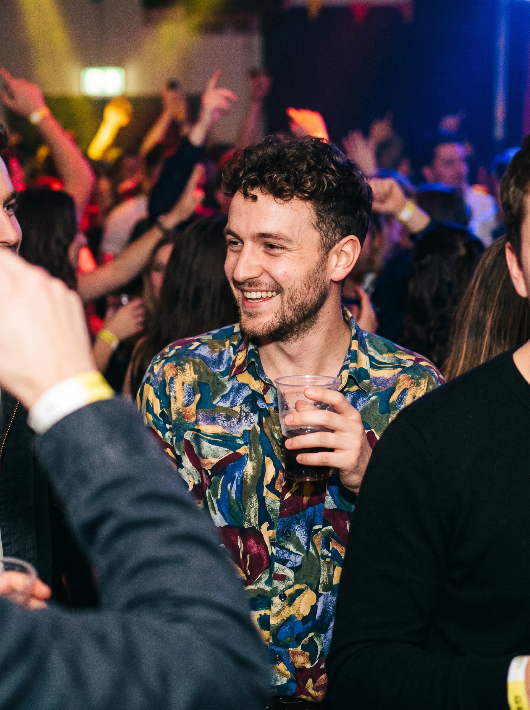 Man cropped from a group photo at a party, other people still visible at the frame edges